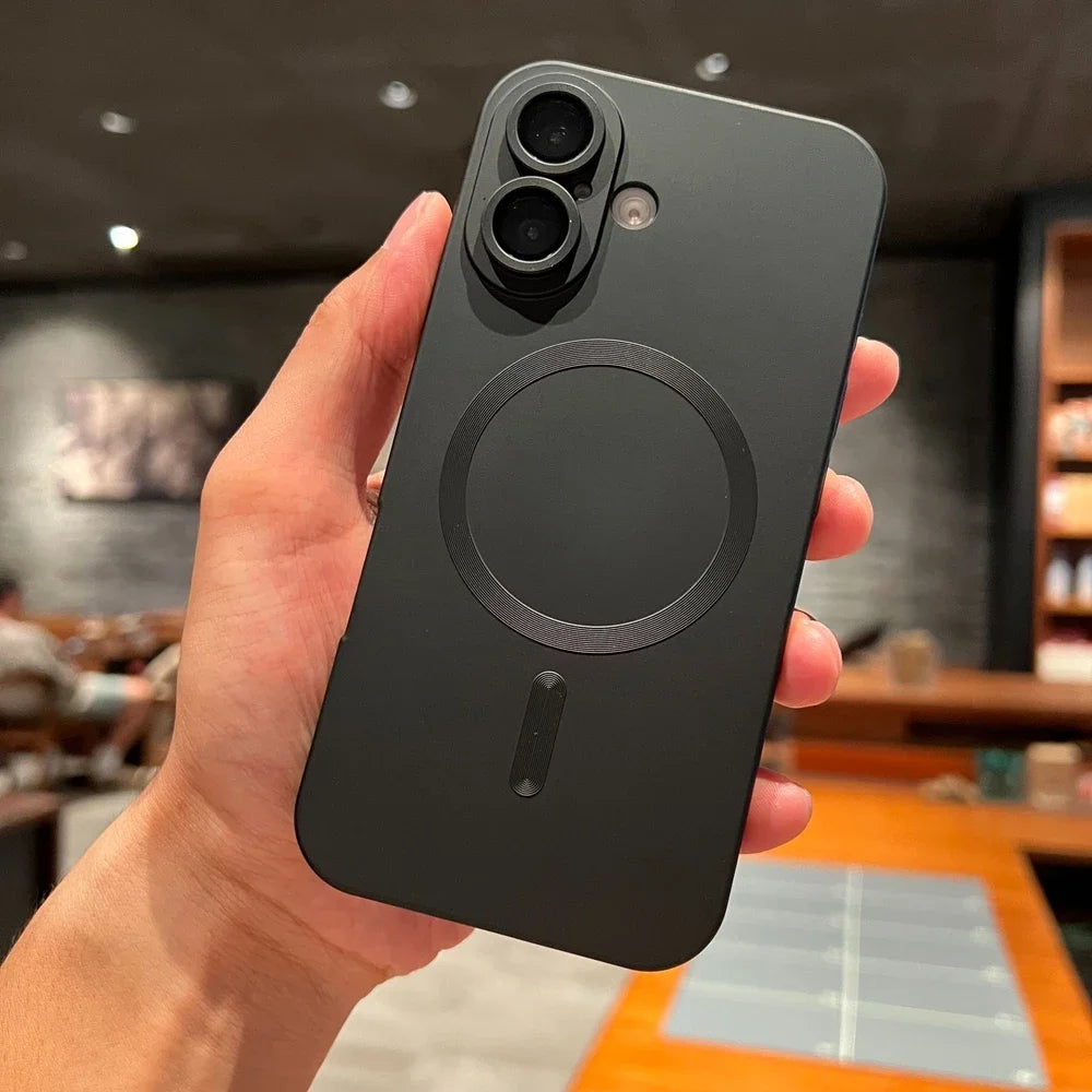 Person holding a black phone case with a blurred indoor background